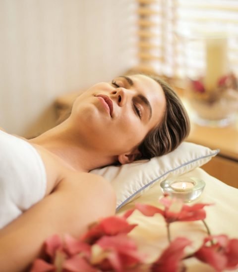 woman in wrapped in white towel lying on bed with eyes closed